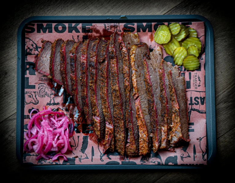 Gesneden brisket whole packer van de BBQ met pickles en rode ui